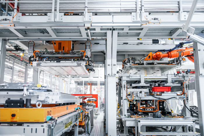 Roboterarme bringen den Deckel für das Batteriepaket. Zunächst wurd der Deckel wasserdicht verklebt, danach wird er verschraubt. (Bild: Audi)